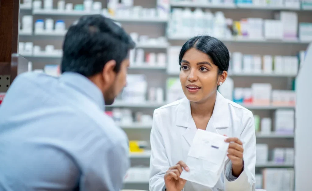 Pharmacist explaining SFA software to customer in pharmacy.